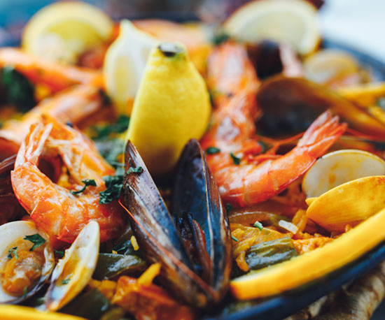 A plate of seafood, including shrimp and clams, with lemon wedges