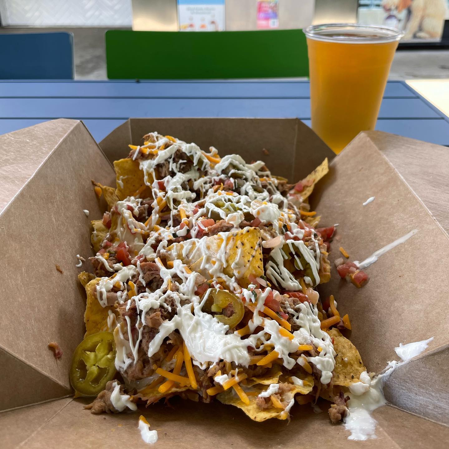 A bowl of nachos with a beer