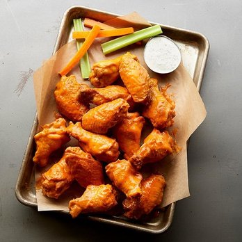A tray of buffalo wings with carrots, celery, and dipping sauce