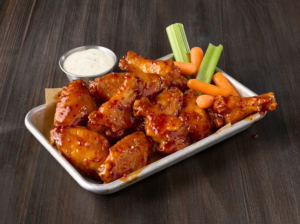 A plate of wings with carrots, celery, and dipping sauce