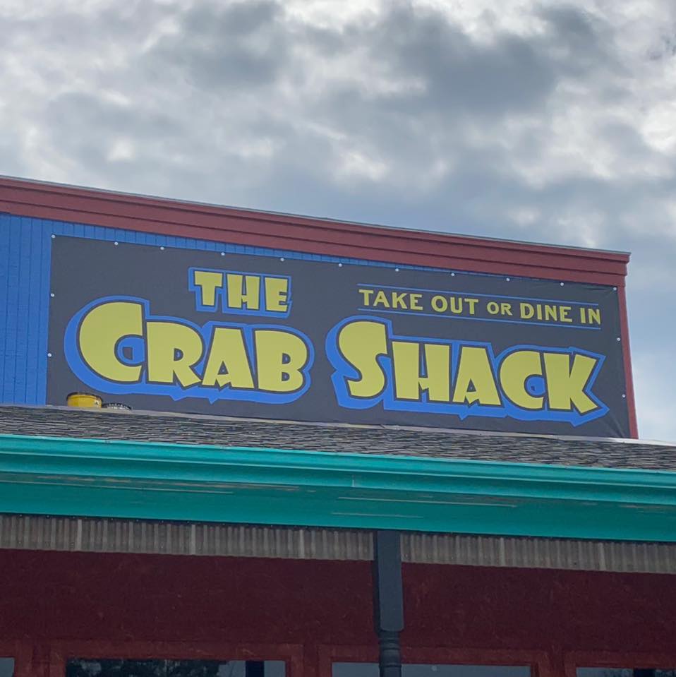 A sign on the exterior of the building reading: The Crab Shack. Take out or dine in