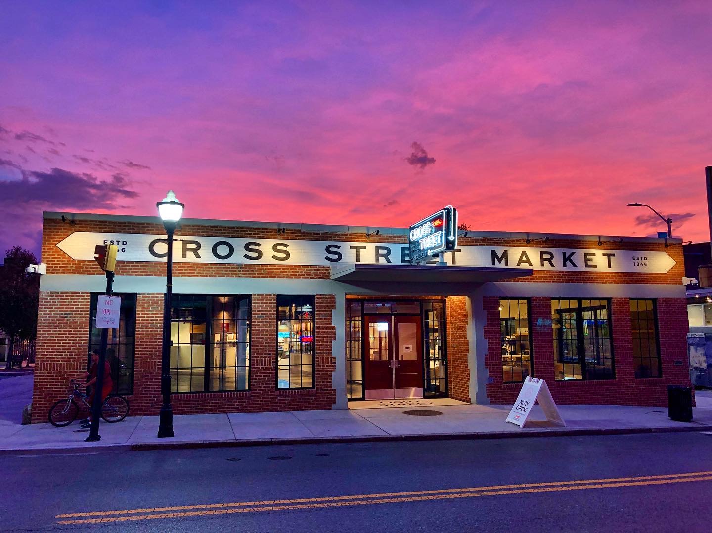 Exterior of Cross Street Market with a colorful sunset in the background