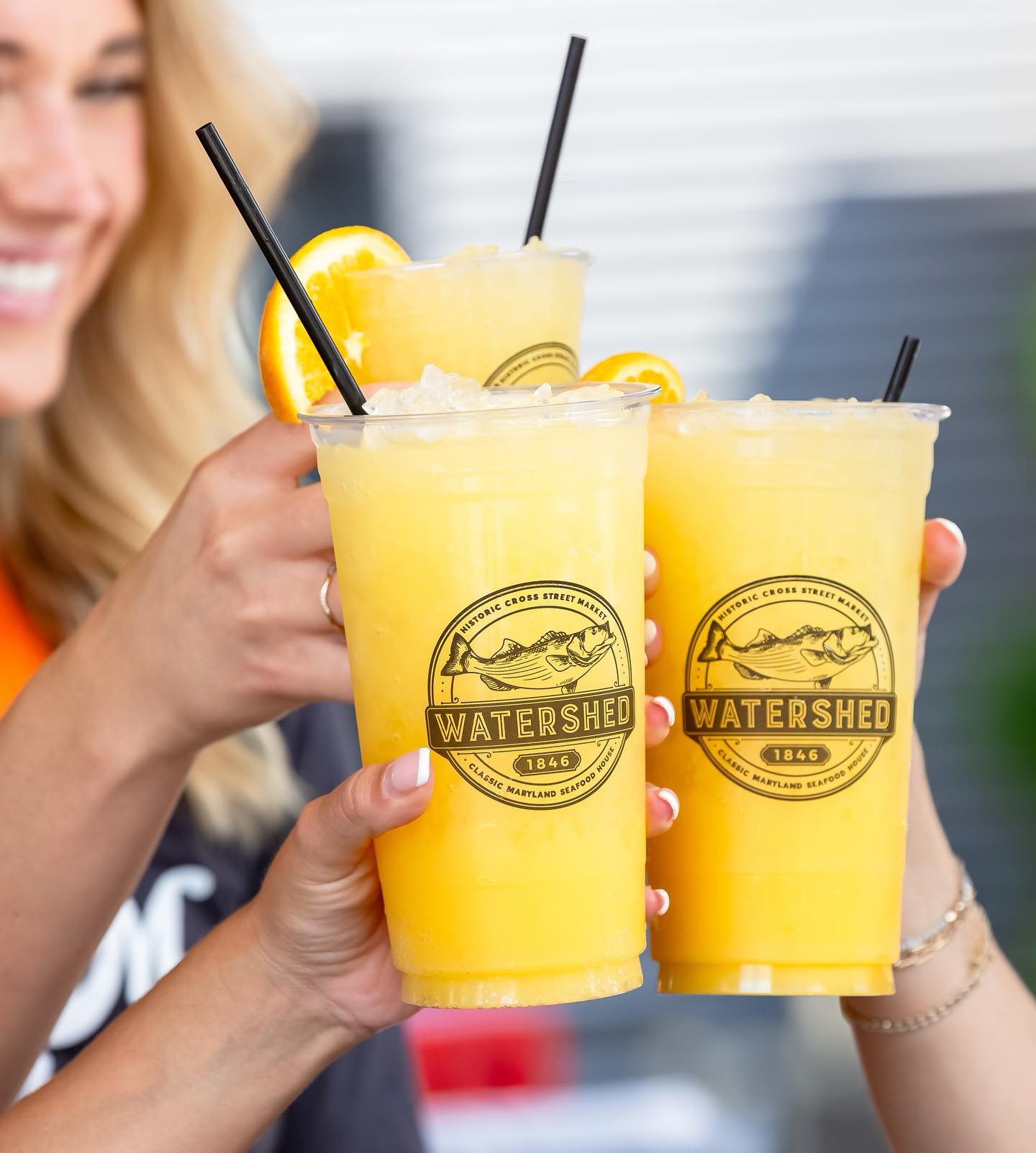 Three people cheers-ing yellow slushie drinks from Watershed