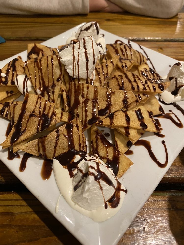 A plate of fried dough, covered in chocolate syrup with vanilla ice cream
