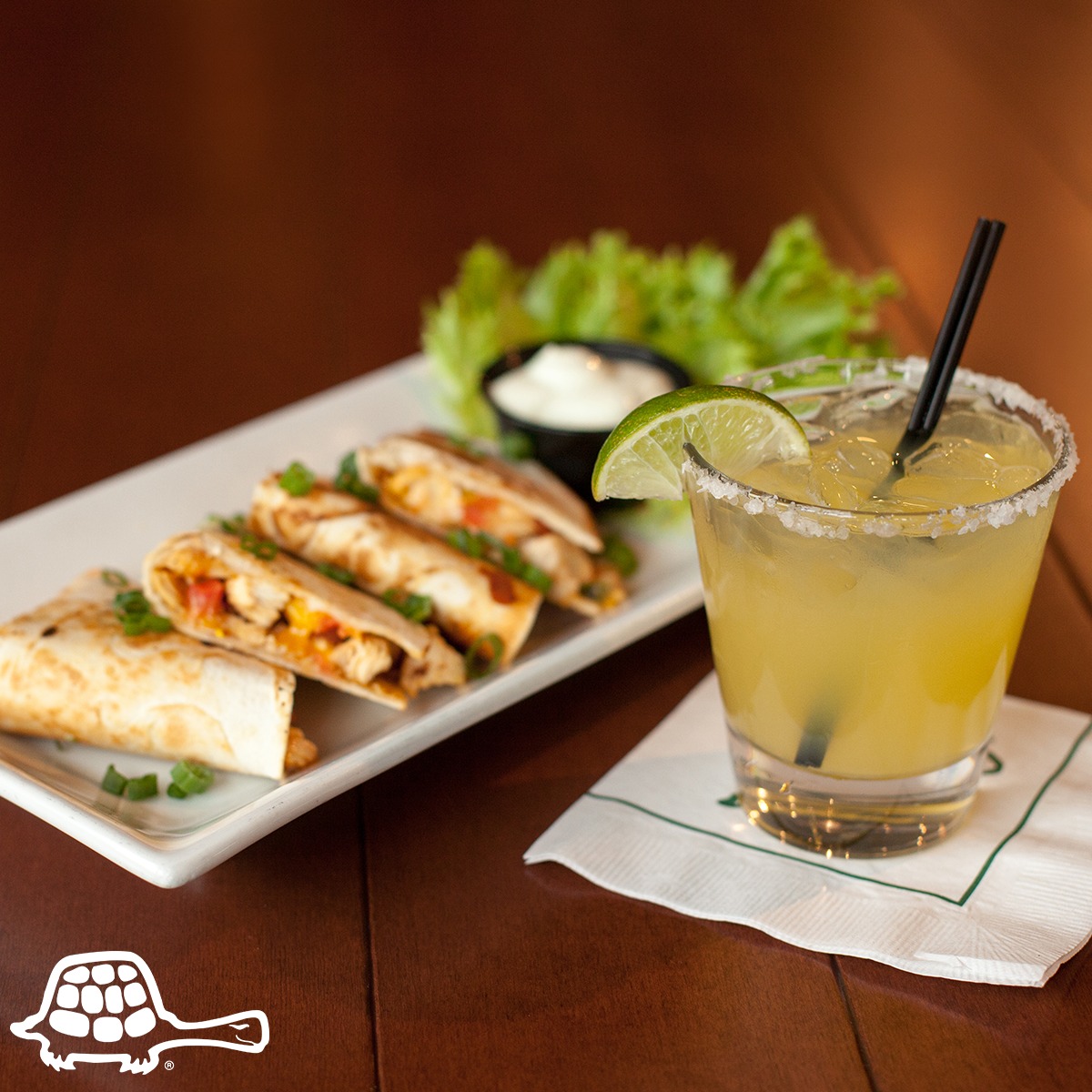 A quesadilla and a cocktail with a lime wedge