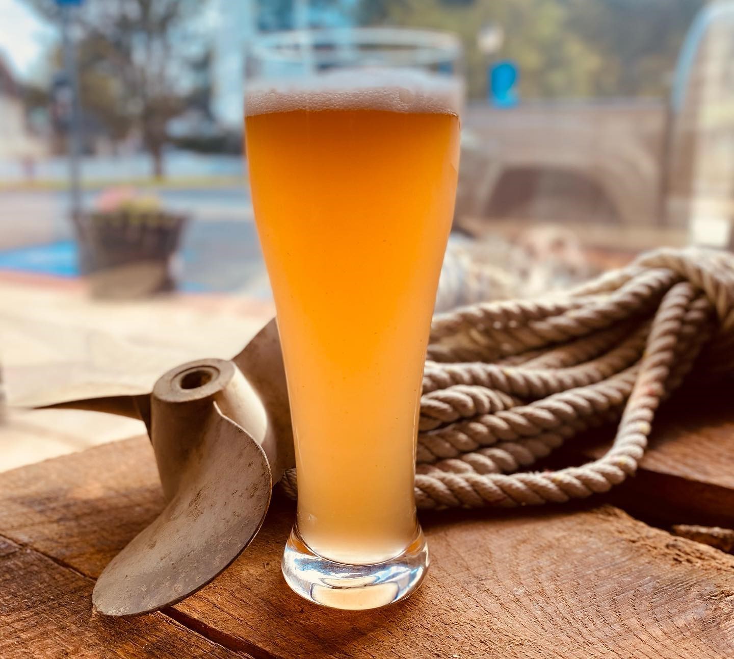 A glass of beer on a wooden table with a boat propeller and rope