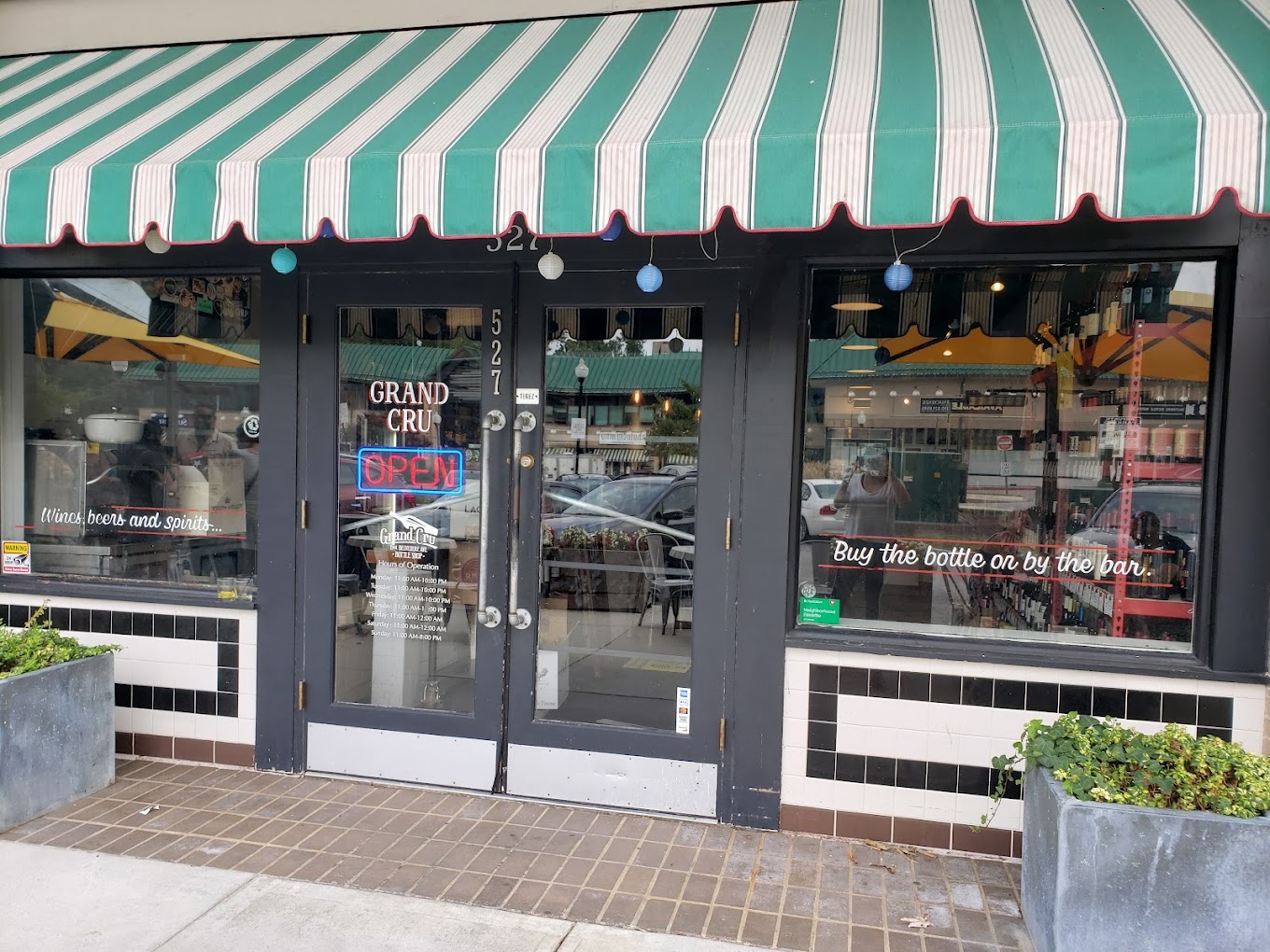 exterior of grand cru bottle shop with a green and white striped awning