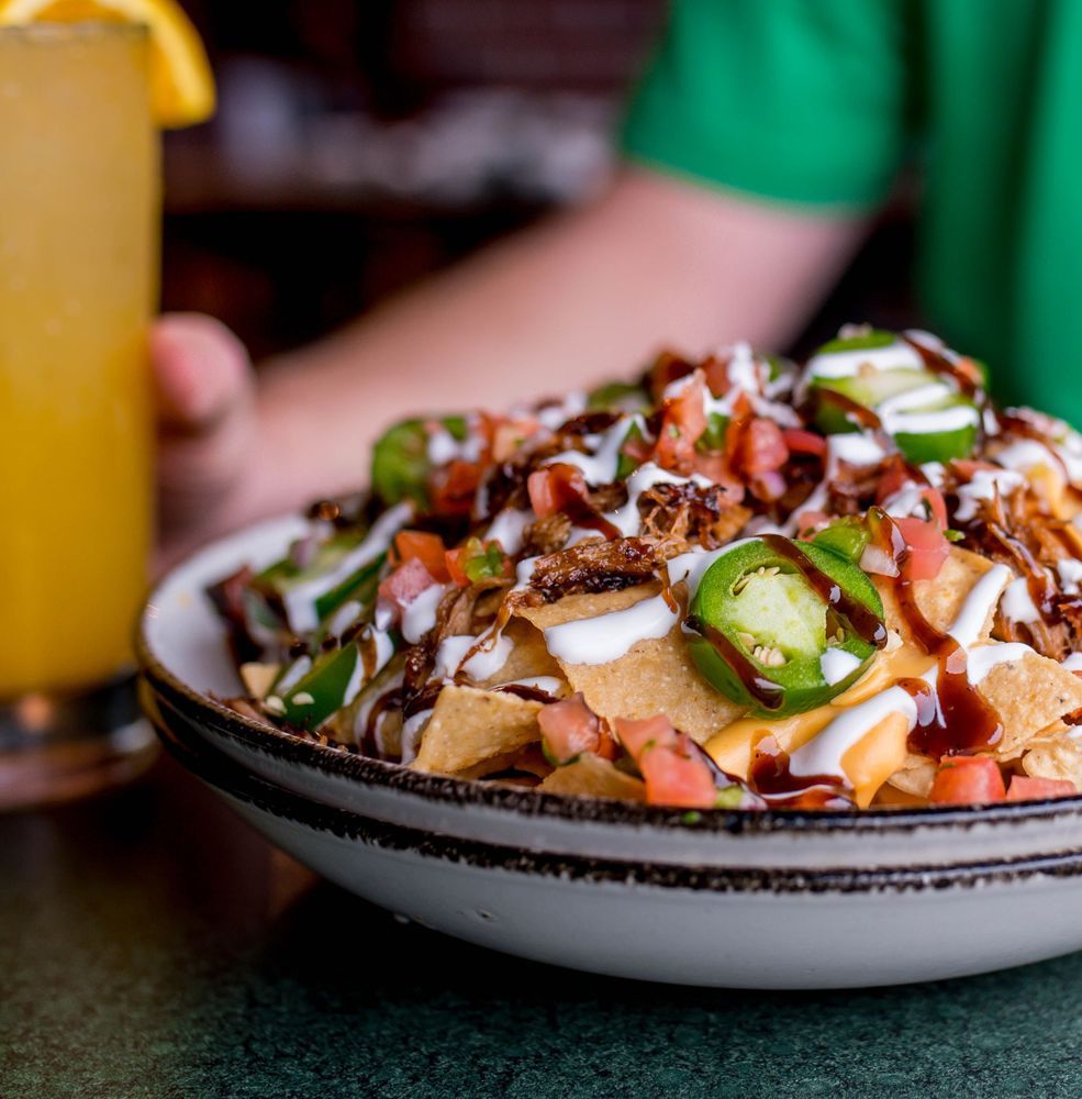 a bowl of nachos with sauce and jalapenos