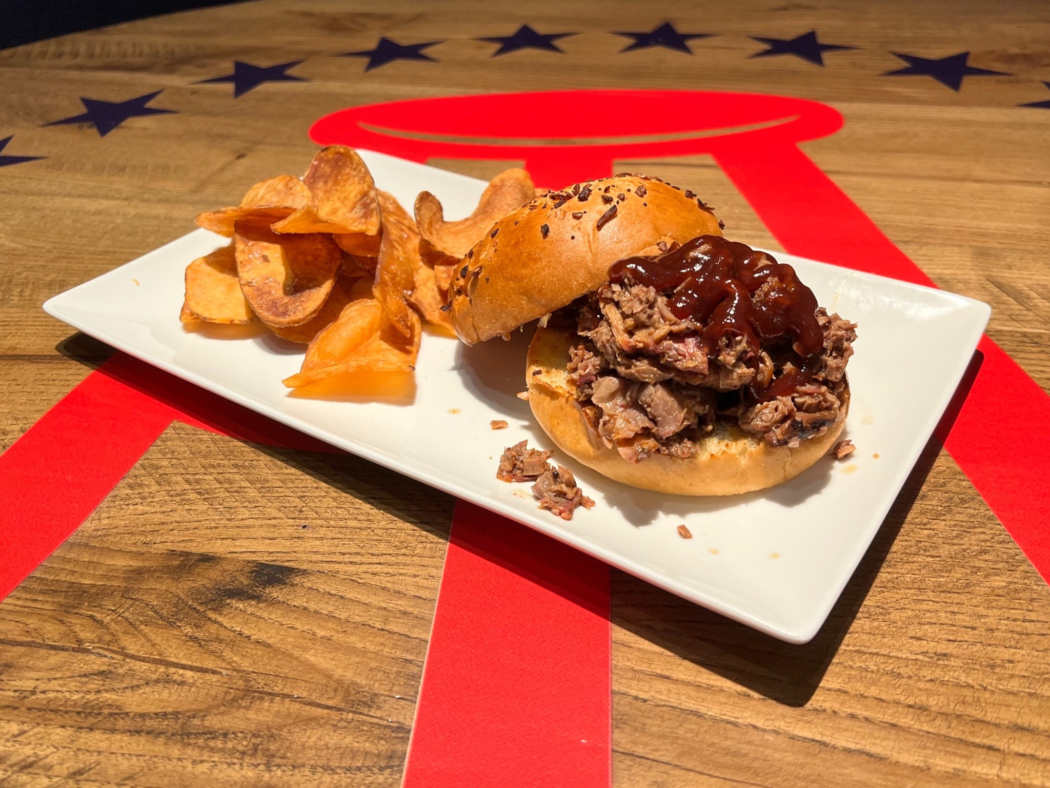 a plate of a bbq sandwich with chips on a table