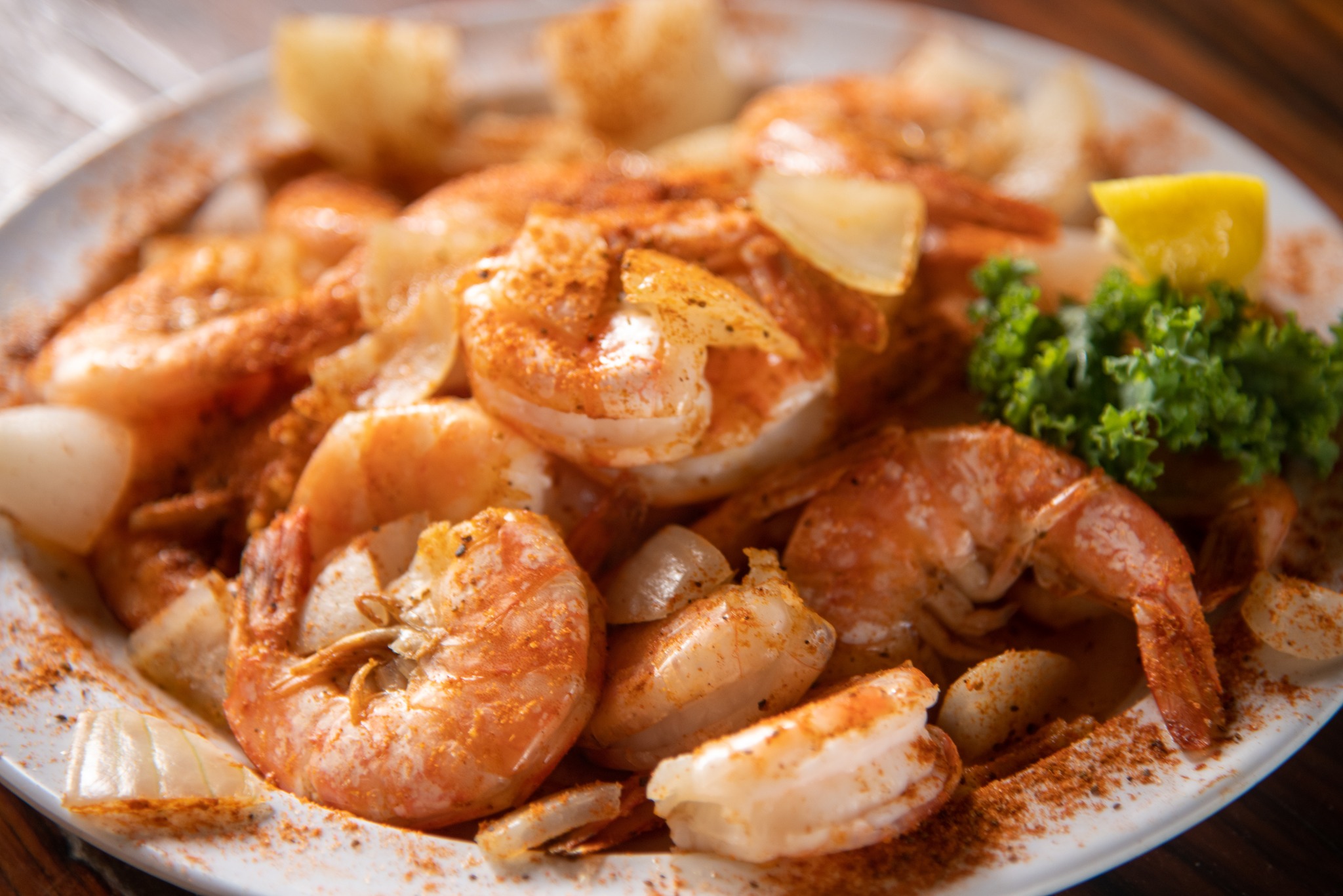a plate of seasoned shrimp with lemon and parsley