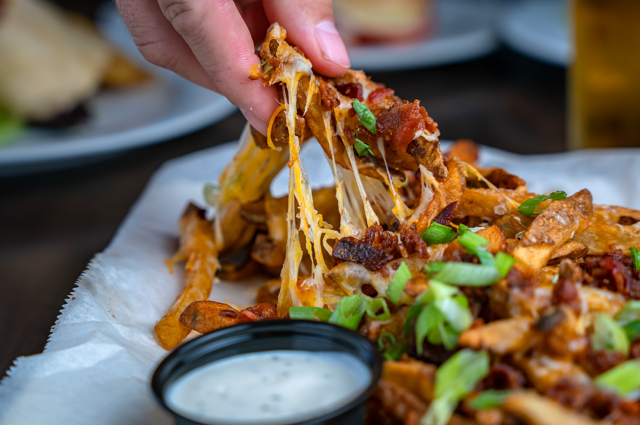 a hand pulling apart loaded cheese fries