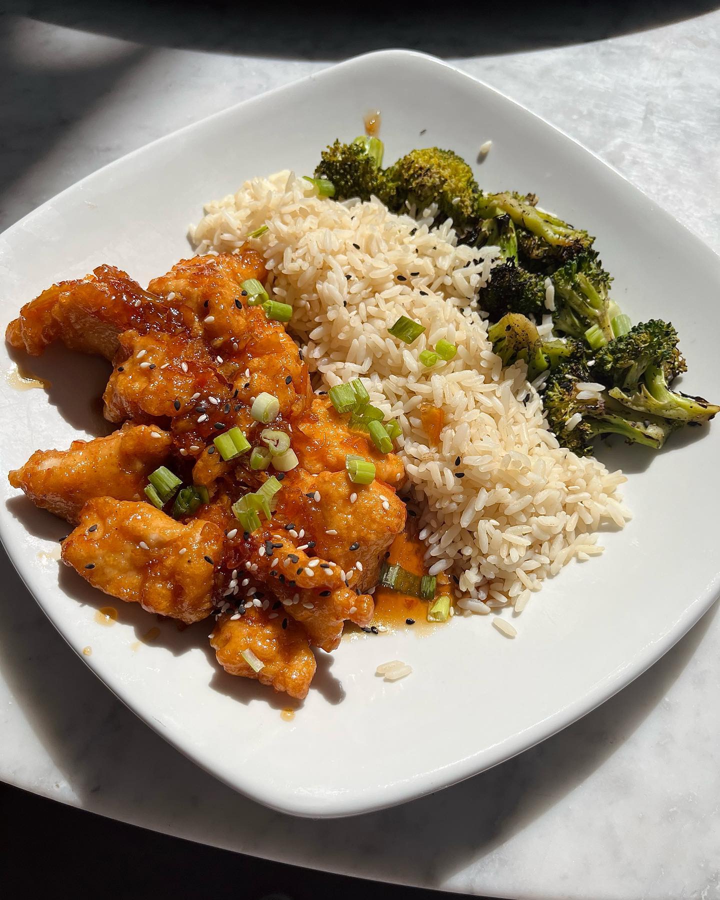 an orange chicken bowl with rice and broccoli