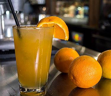 an orange cocktail next to oranges