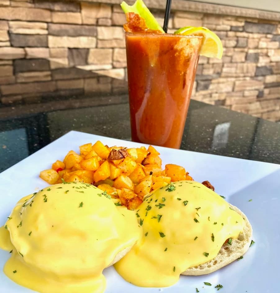 a plate of eggs benedict and a bloody mary