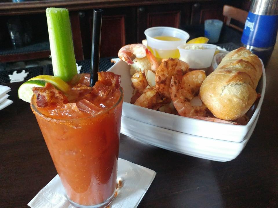 A bowl of shrimp with bread and a bloody mary