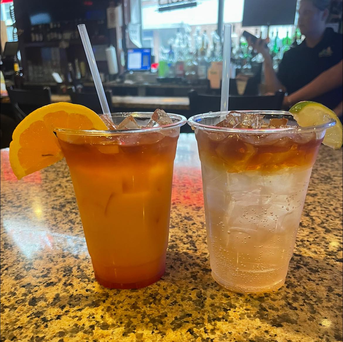 a hurricane cocktail with an orange wedge and a dark and stormy cocktail with a lime wedge