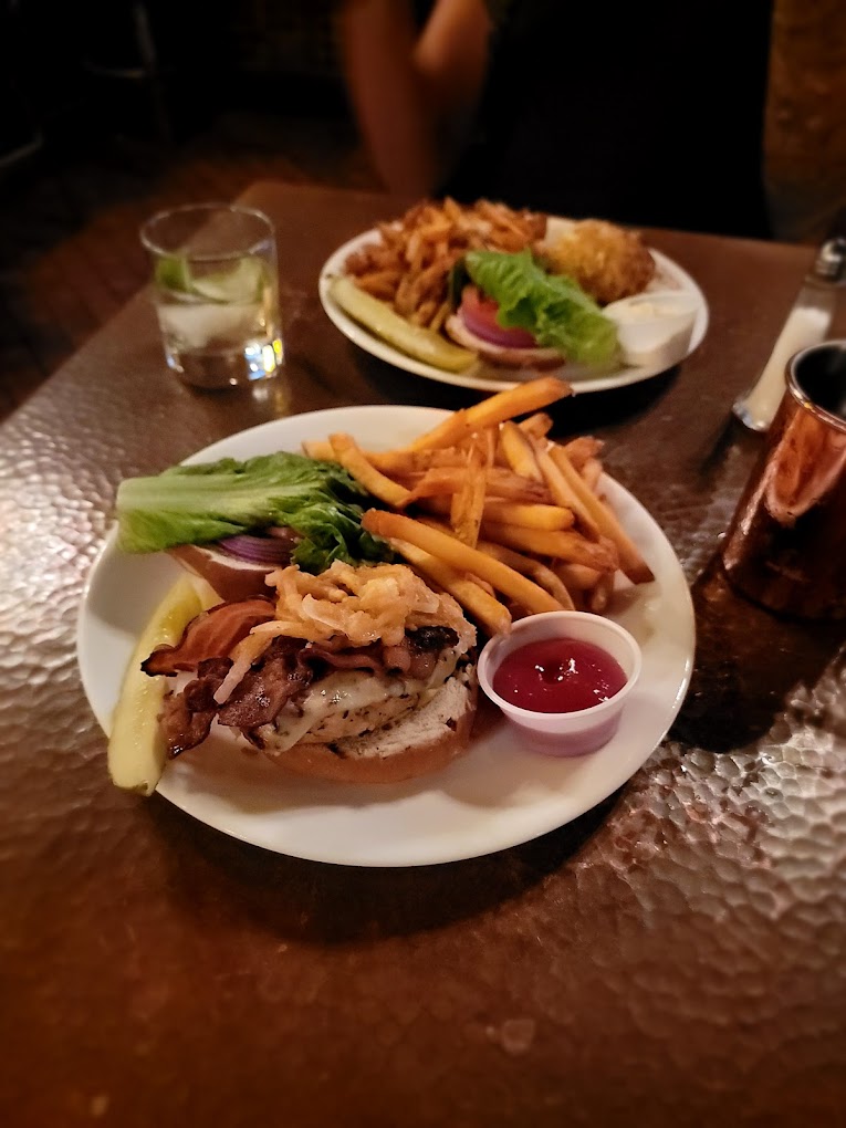 two plates of burgers with fries on a table