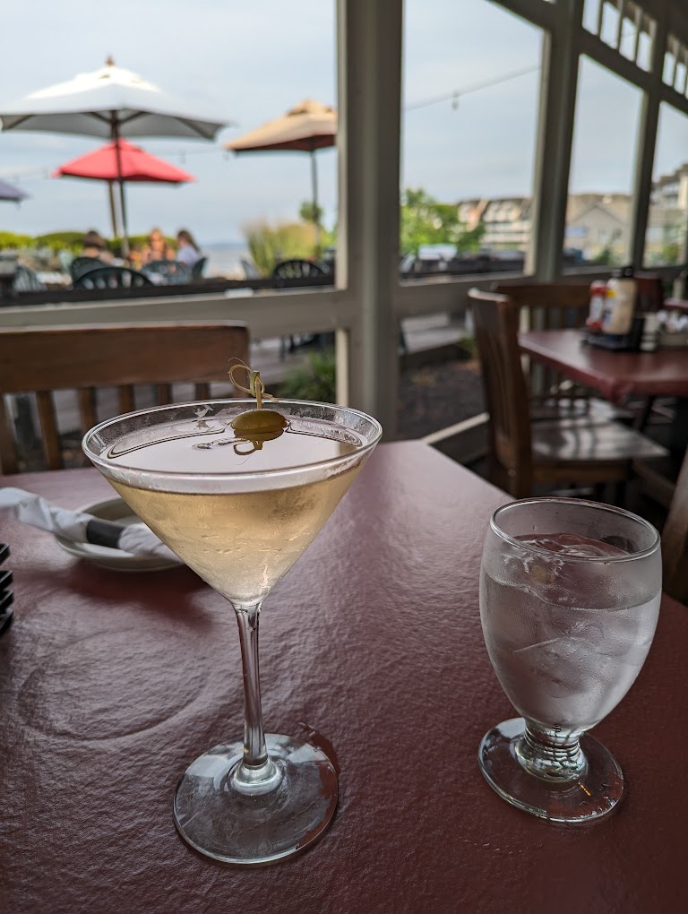 Martini and glass of water on a table facing the waterfront