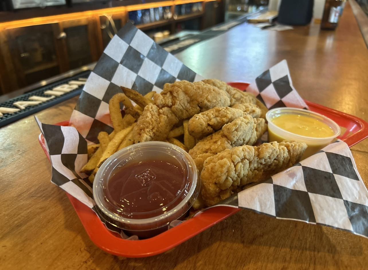 a basket of chicken tenders and fries with dips