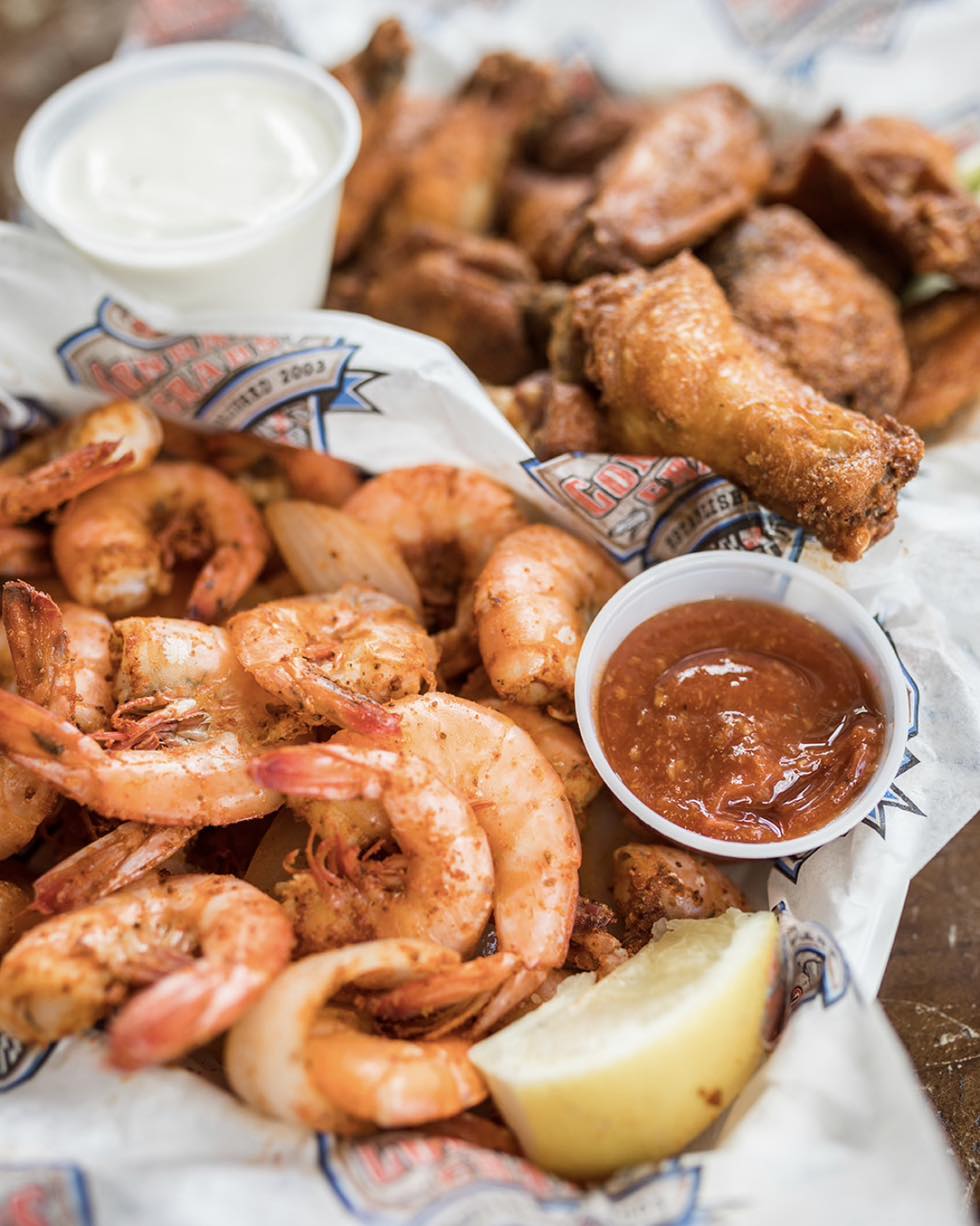 a basket of shrimp and a basket of wings