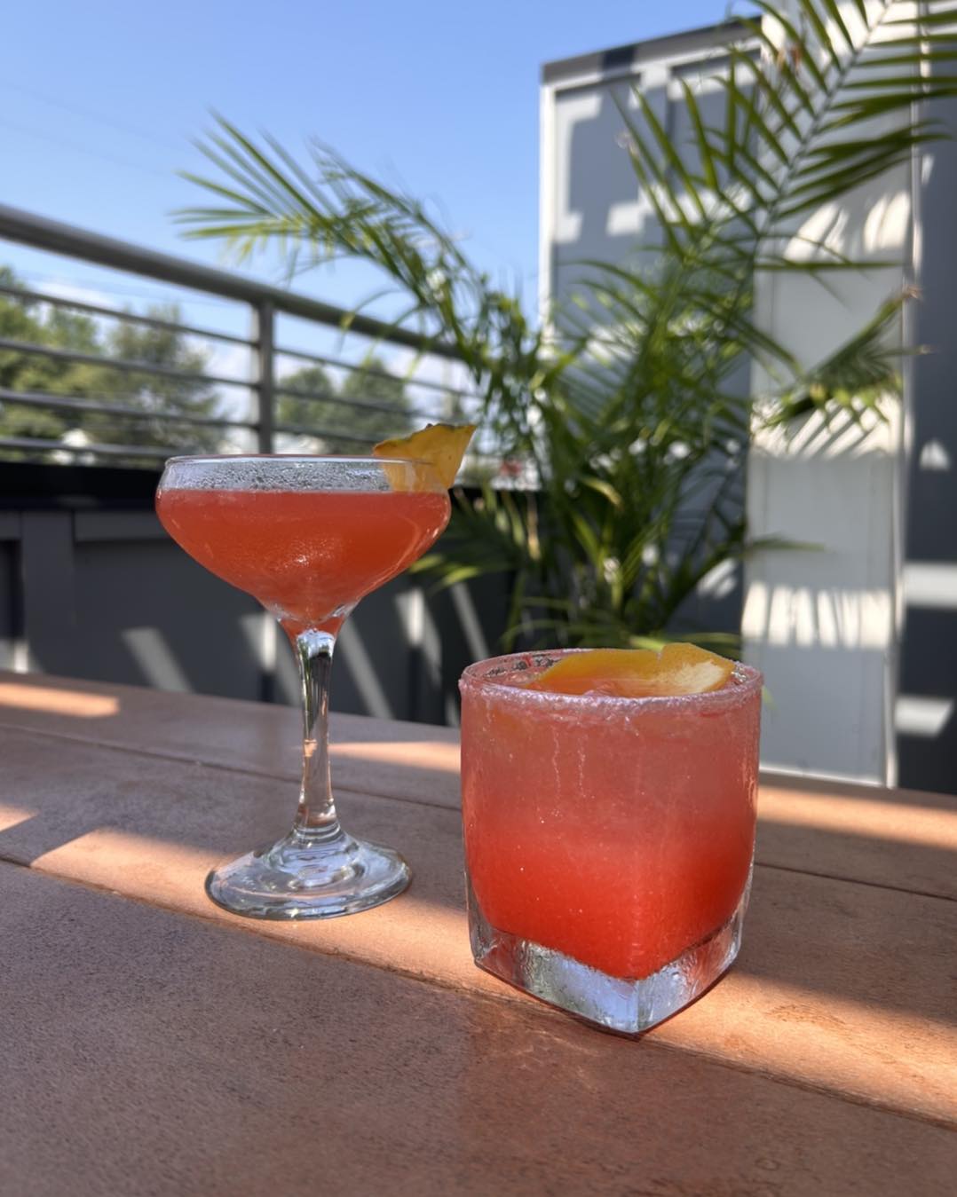 two pink cocktails on a table outside