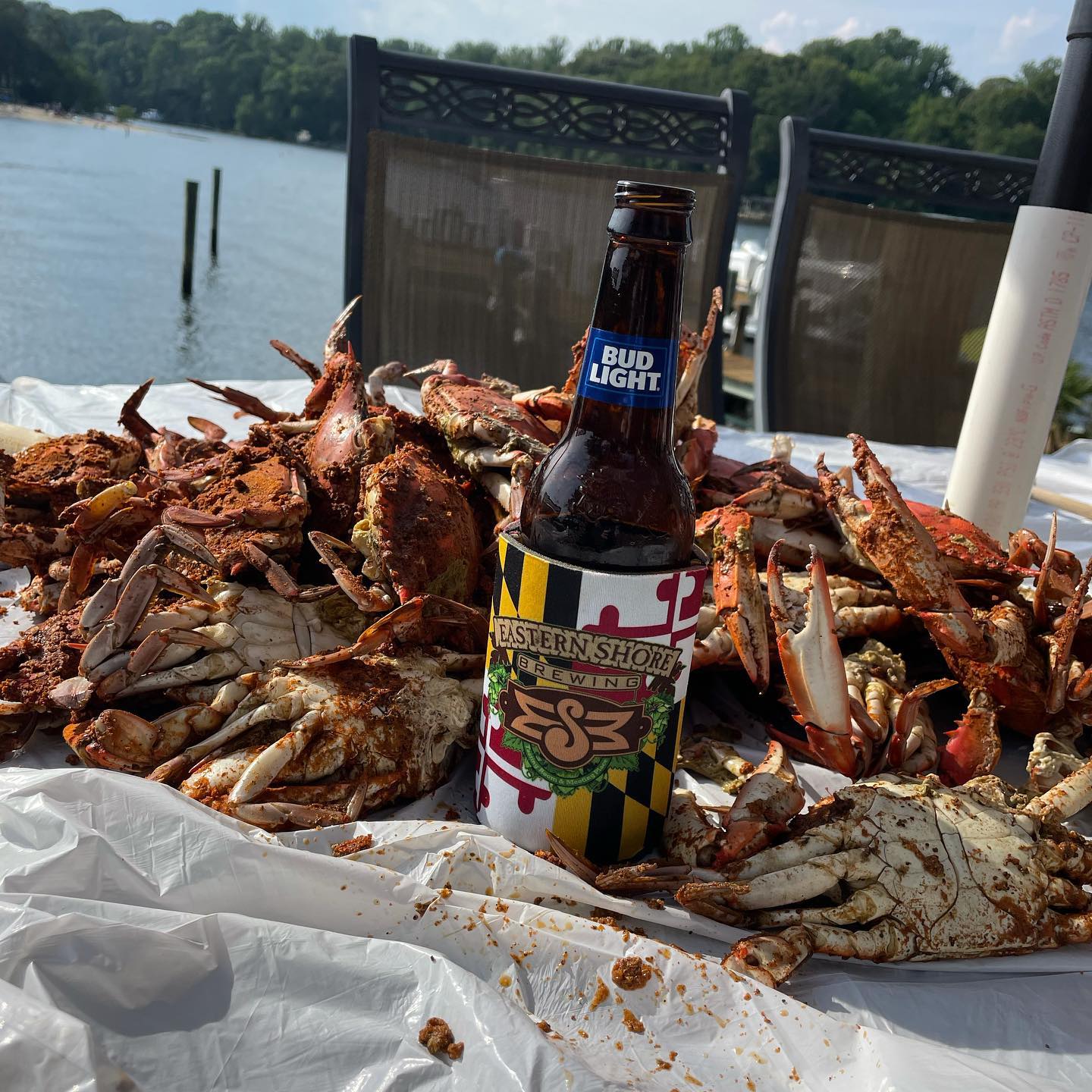 a pile of crabs on a table with a bottle of bud light