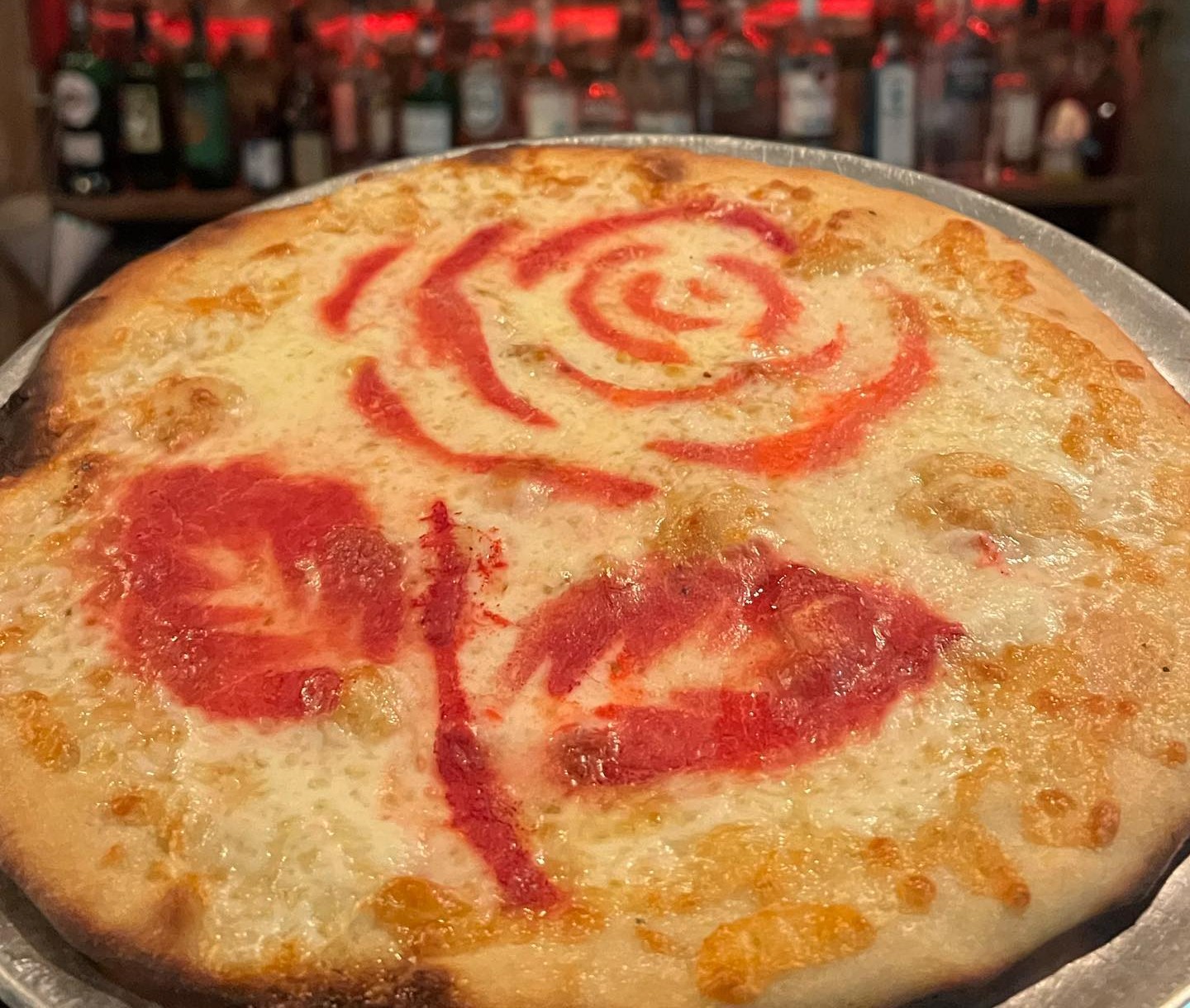 a pizza with sauce in the shape of a rose