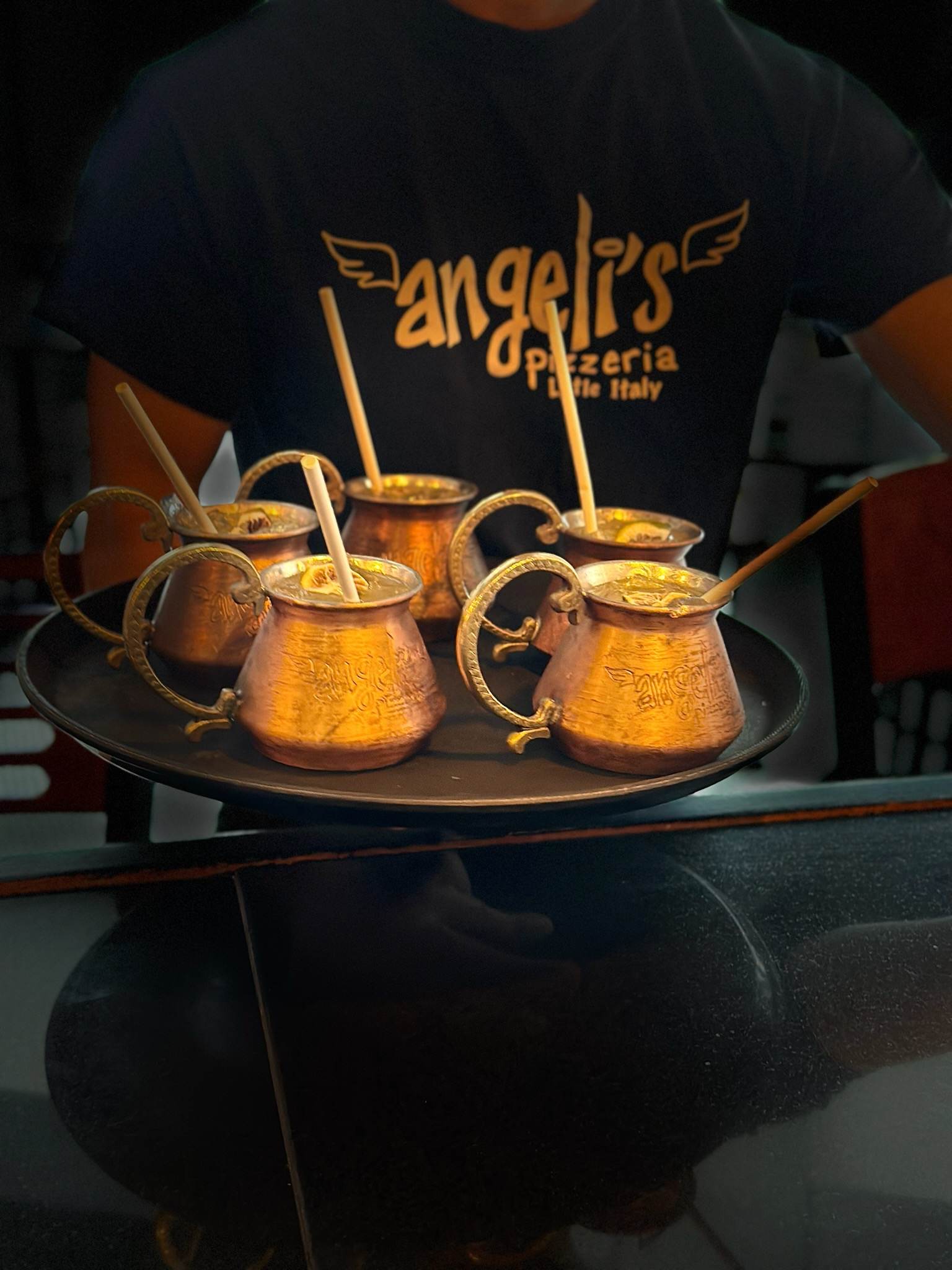 a server holding a tray of cocktails in copper mugs