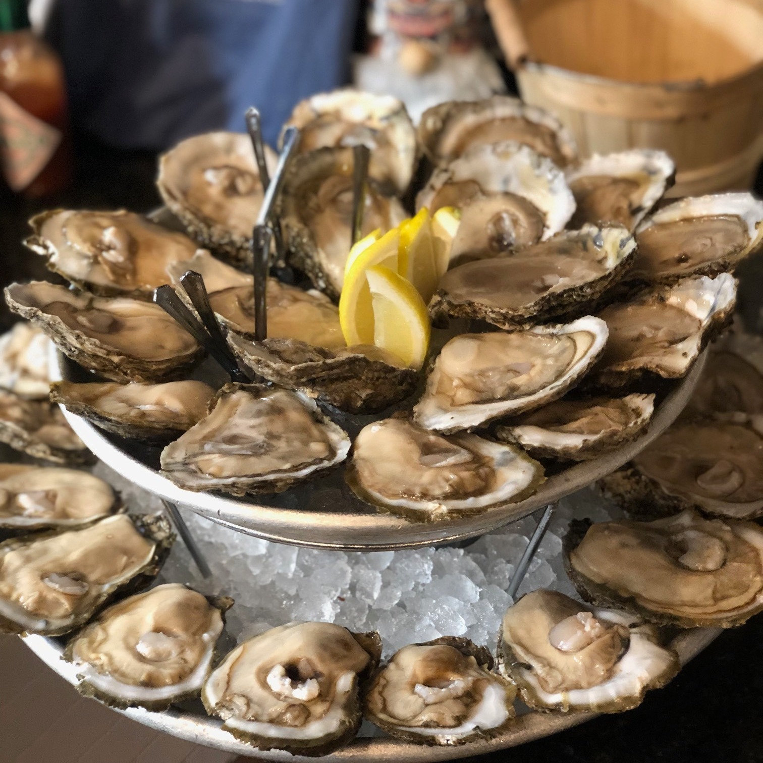a platter of oysters on ice with lemon wedges