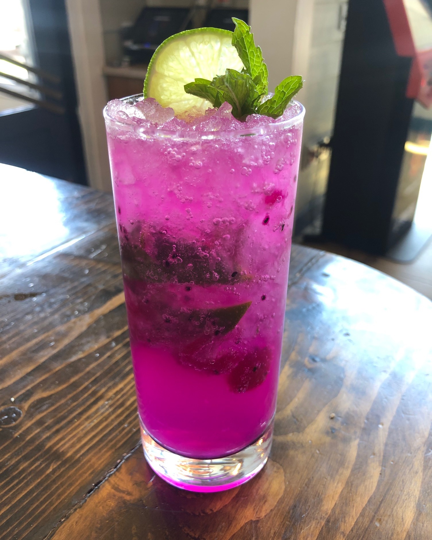 a purple drink with raspberries, mint, and a lime wheel