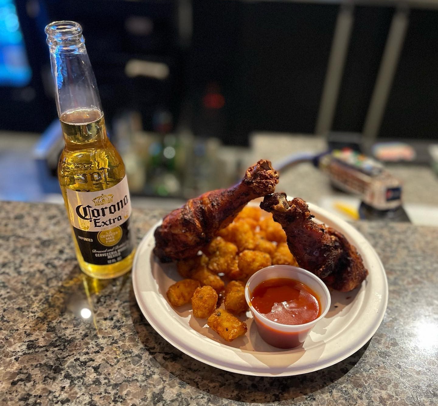 two chicken thighs with tater tots and a bottle of corona