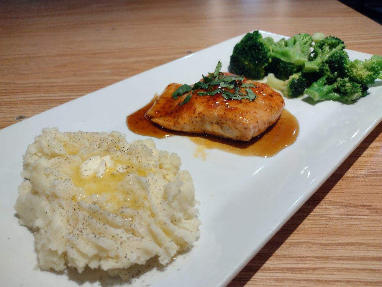 a plate of salmon, mashed potatoes, and broccoli