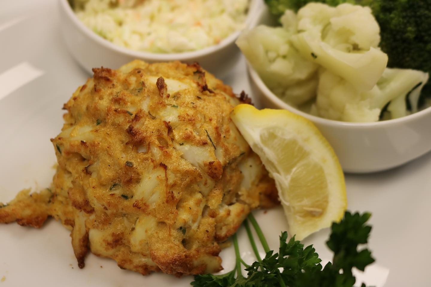 a crab cake with a lemon wedge and two sides