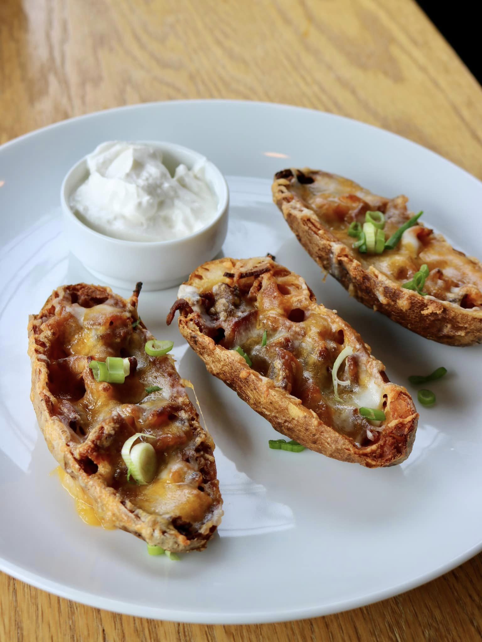 three potato skins with sour cream on a plate