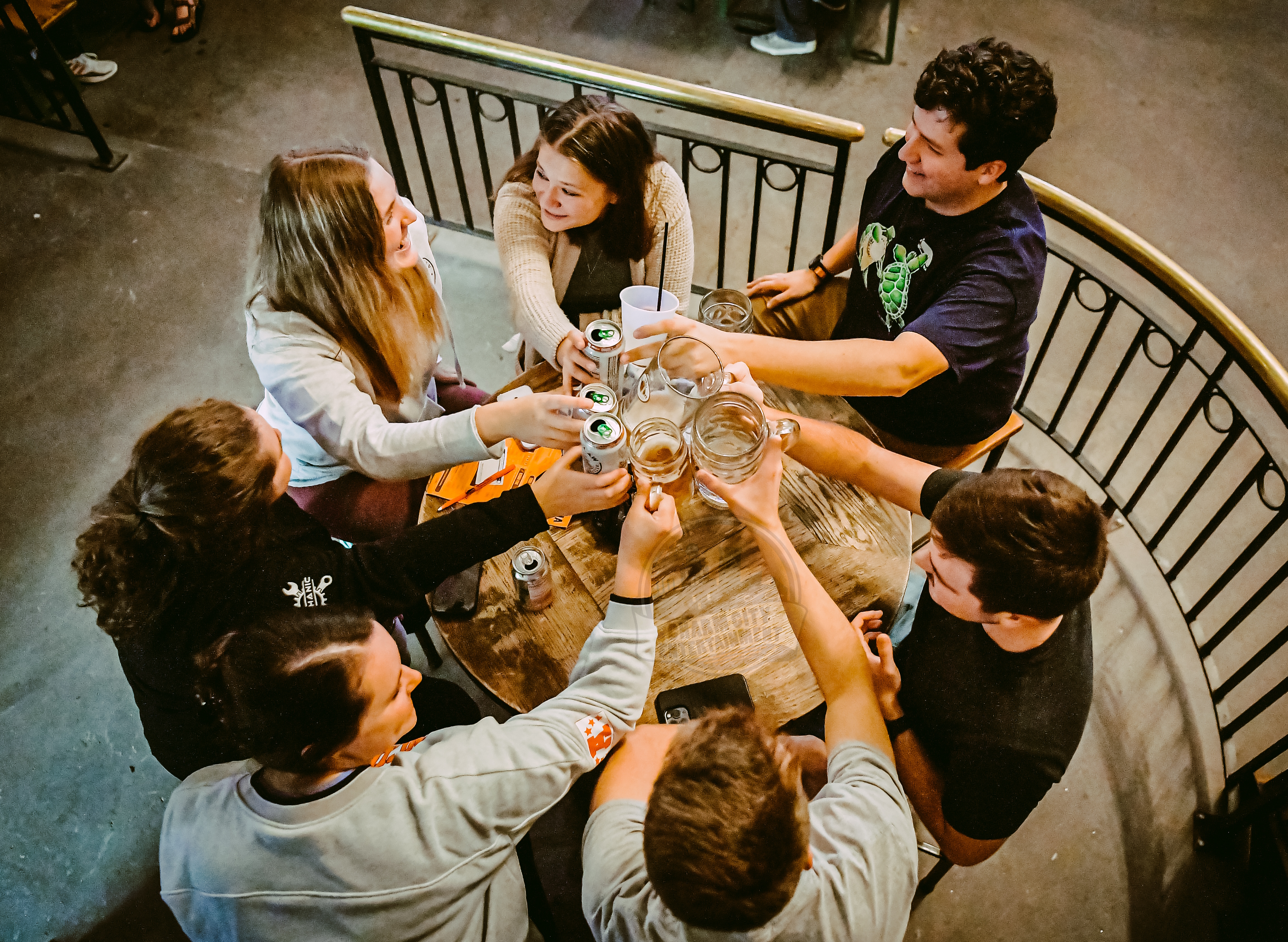 a trivia team sitting around a table cheersing their glasses