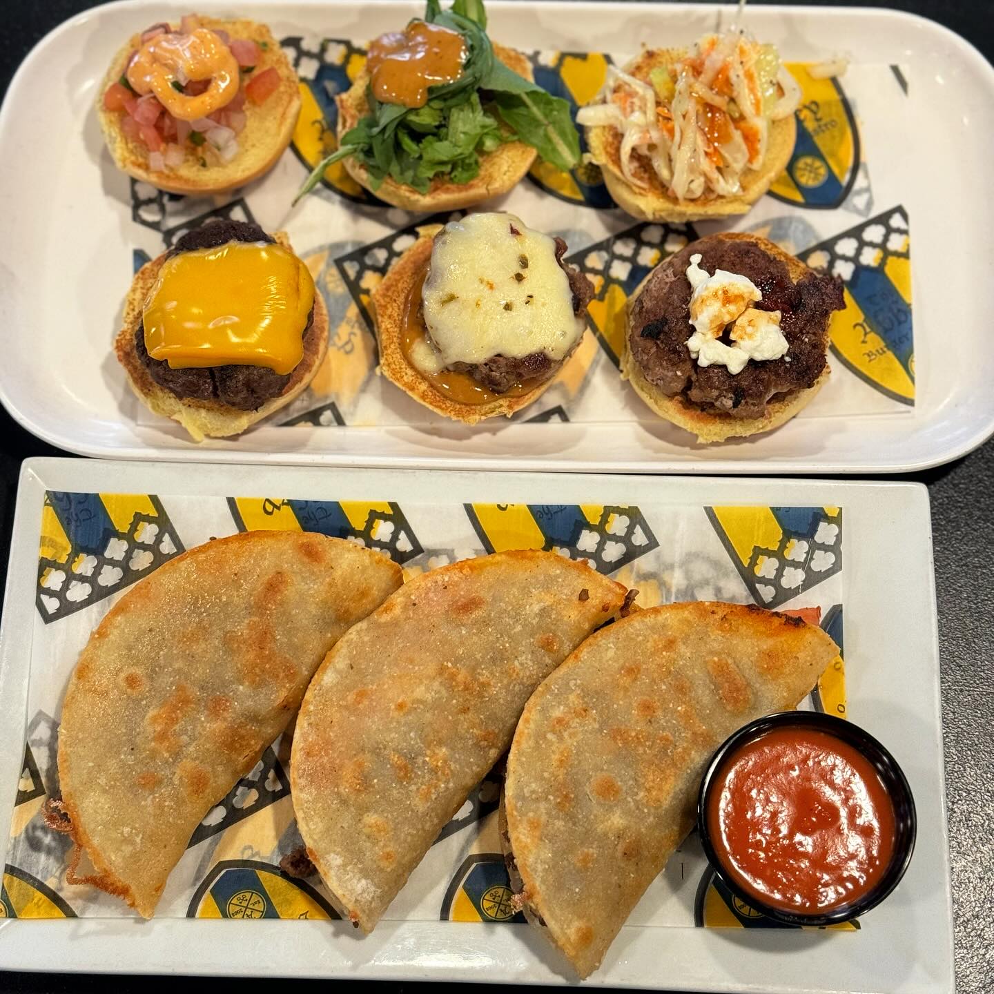 a plate of three tacos with dip and a plate of three mini burgers