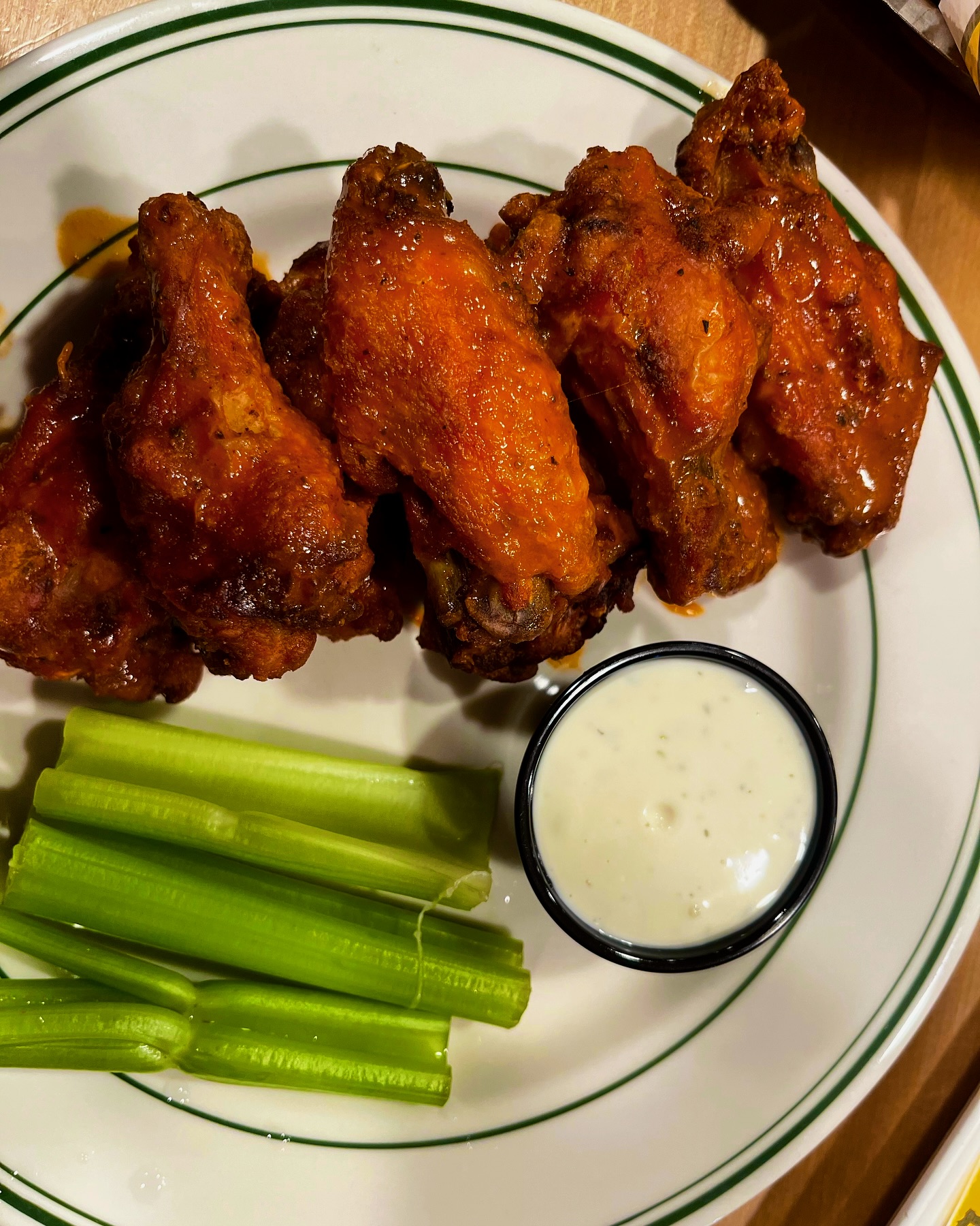 a plate of wings with celery and dip