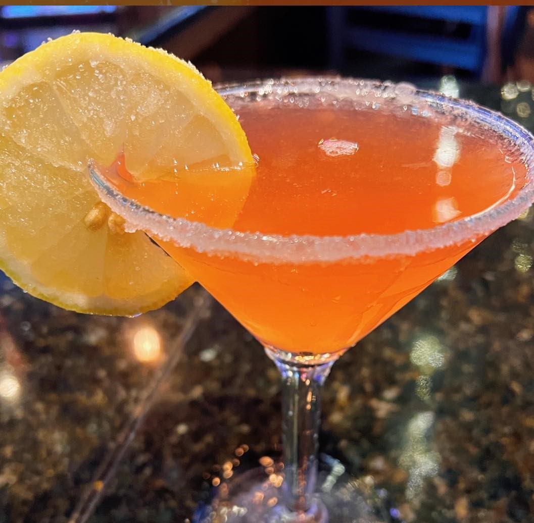 an orange cocktail with a sugar rim and candied lemon wheel