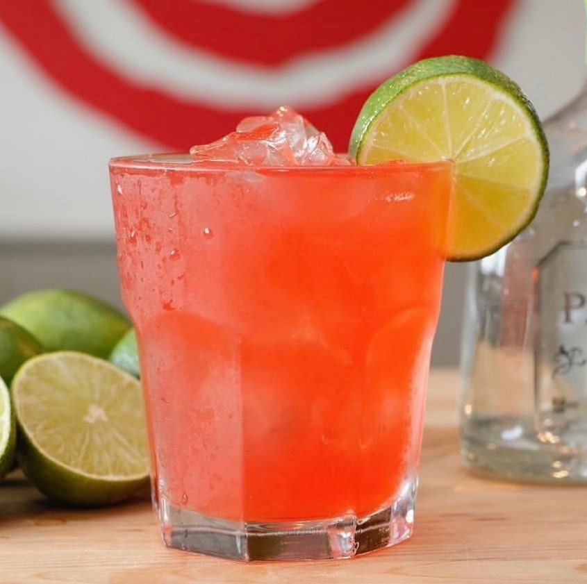 a pink cocktail with a lime wheel
