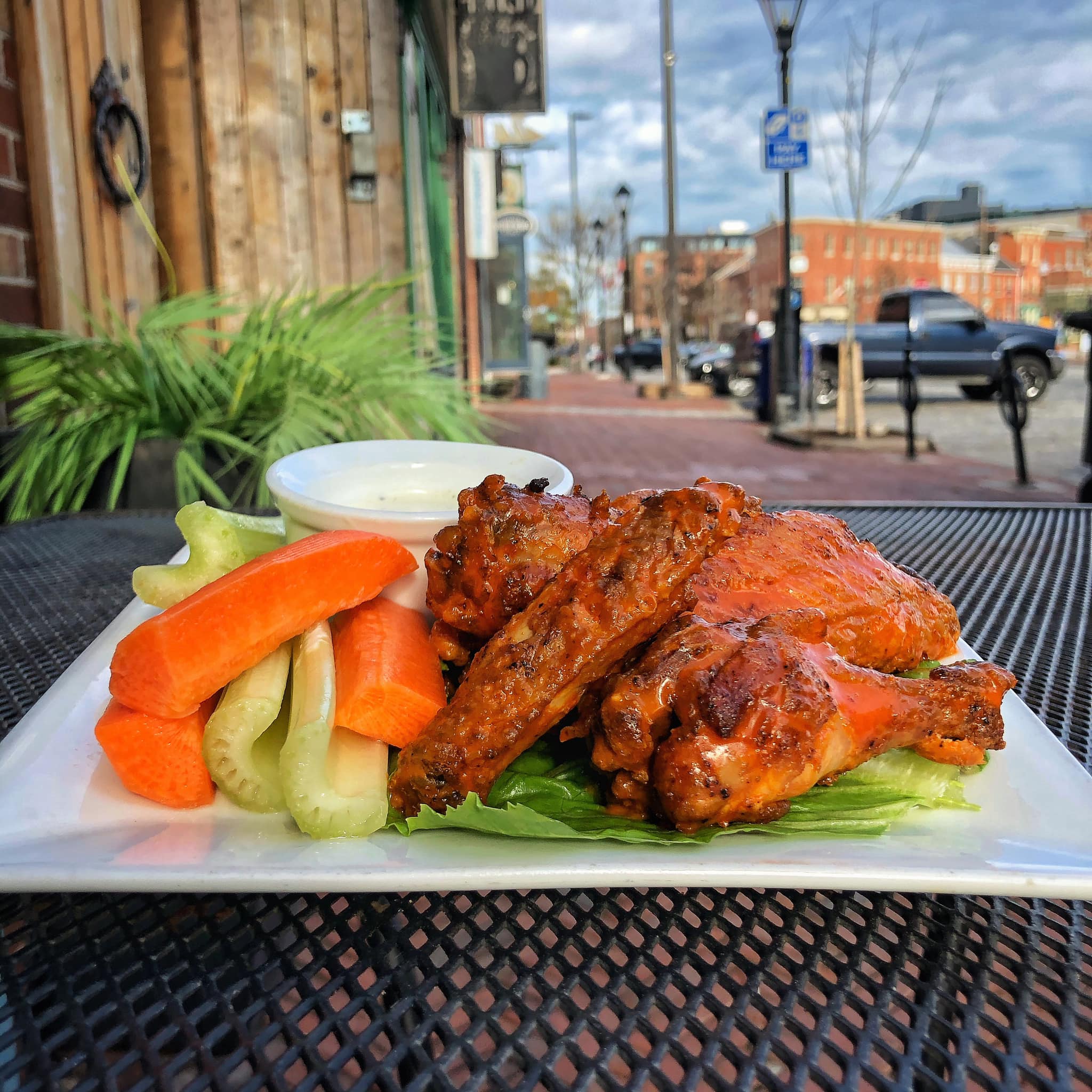 a plate of wings with celery, carrots, and dip