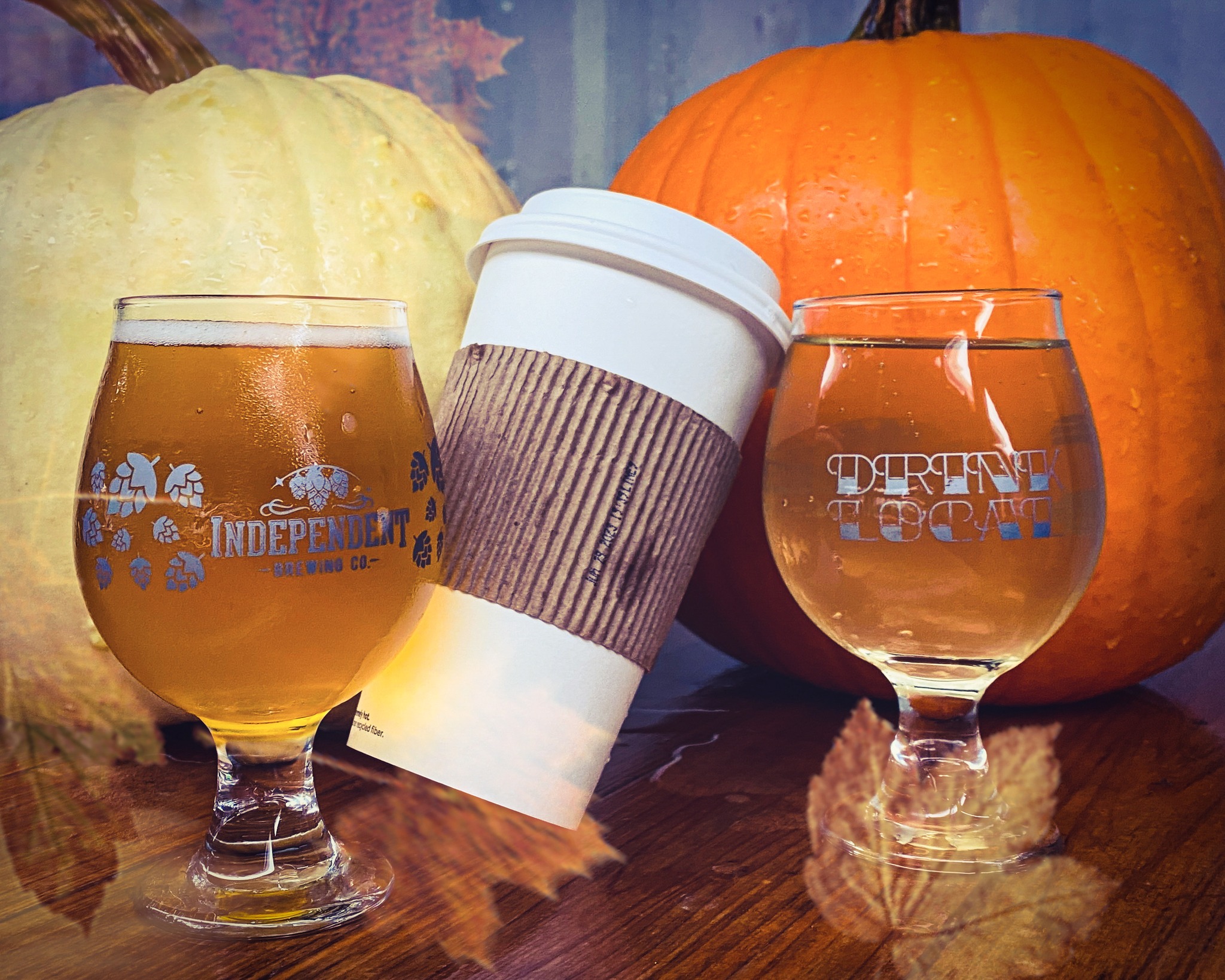 two glasses of beer, a coffee cup, and two pumpkins